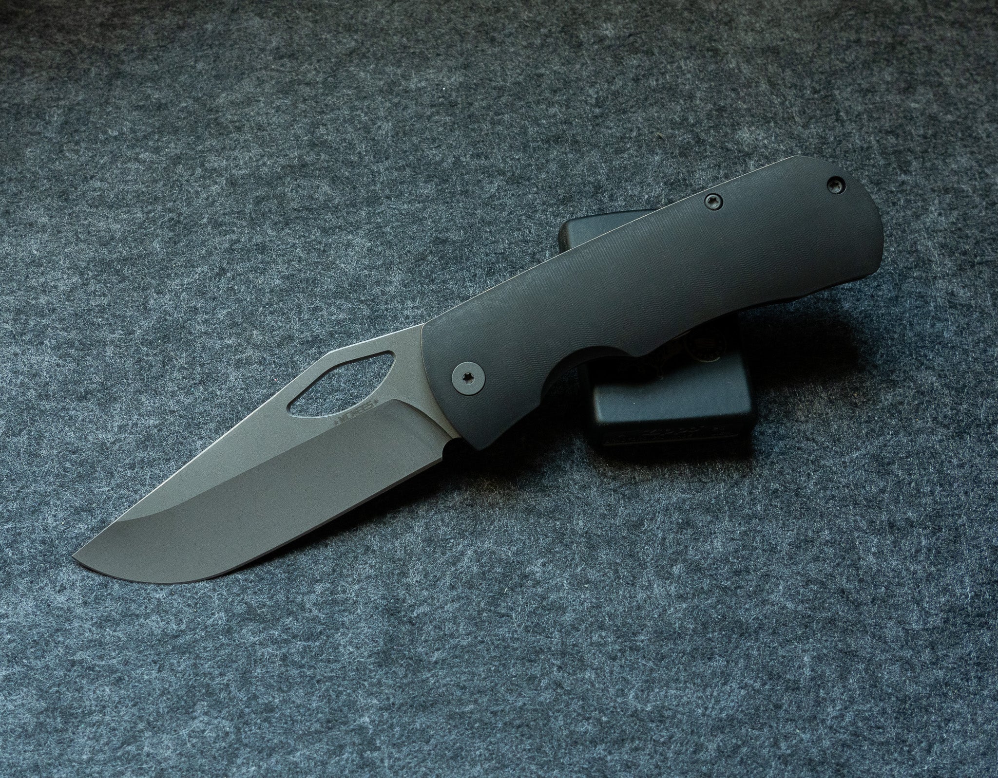 Little Dixon folding pocket knife with a smooth dark handle shown open against a grey felt background