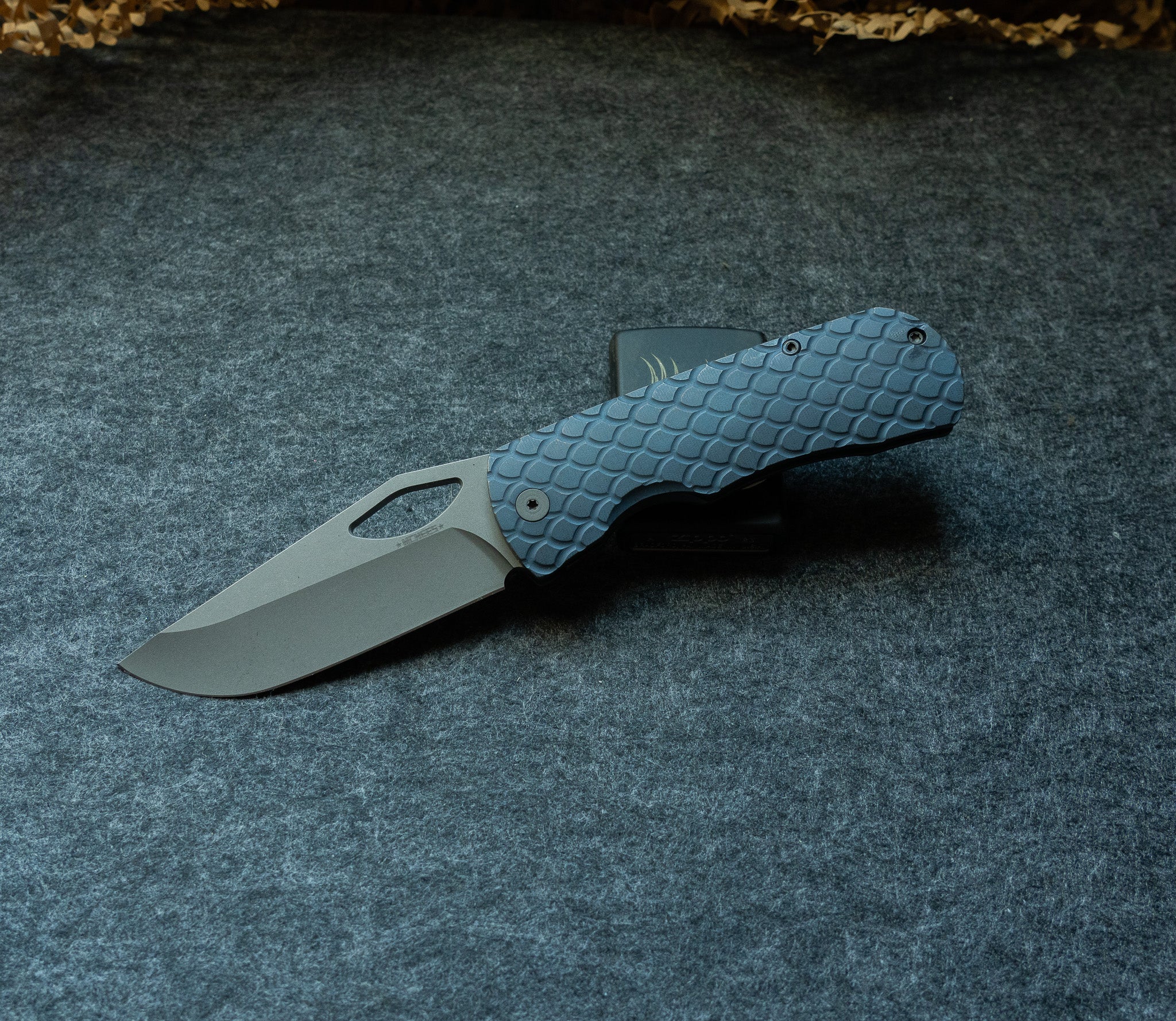 Little Dixon folding pocket knife with a dragon scale textured blue handle shown open against a grey felt background